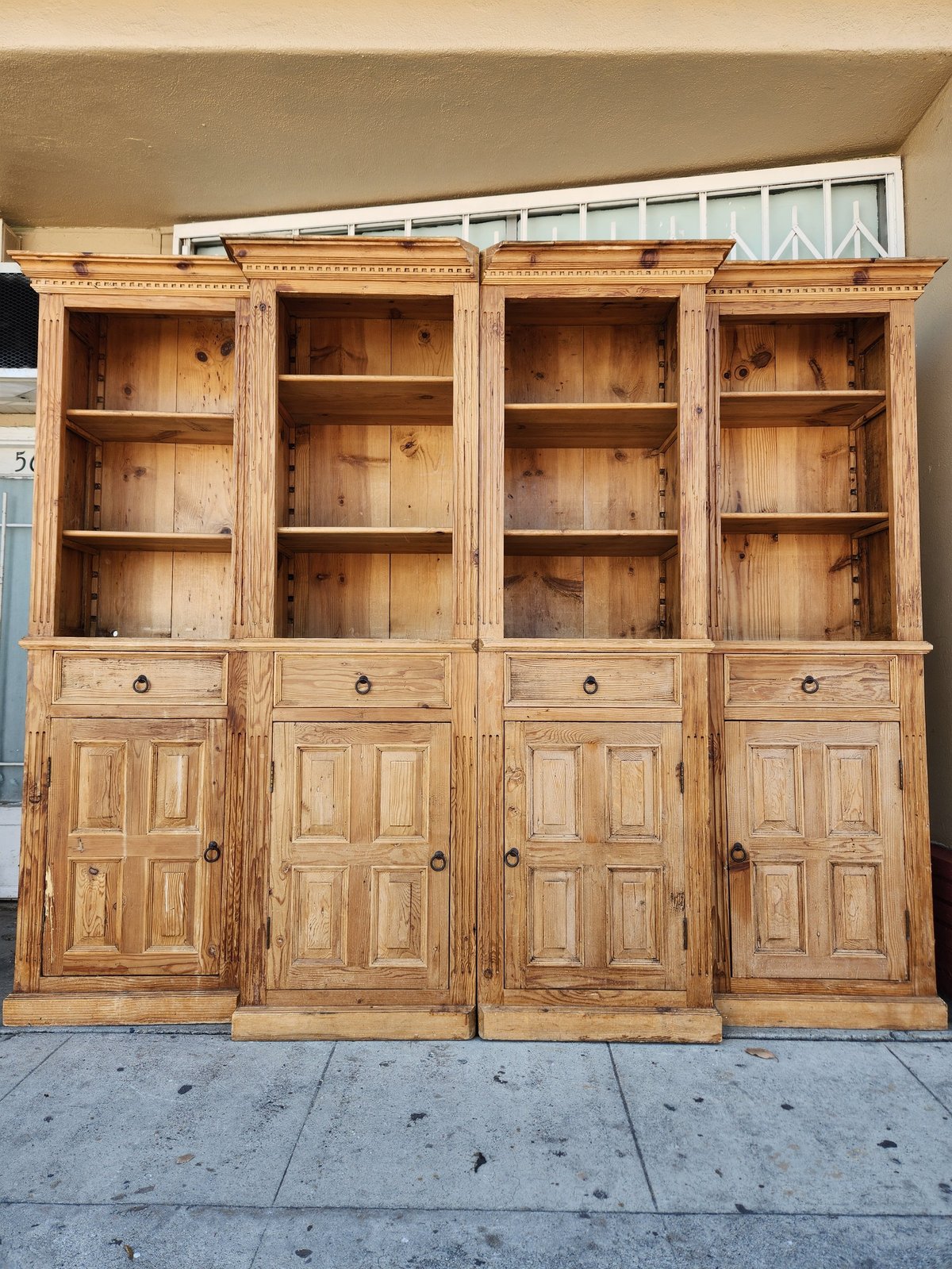 Large wooden cabinet with four glass-fronted upper sections and four enclosed lower cabinets with paneled doors