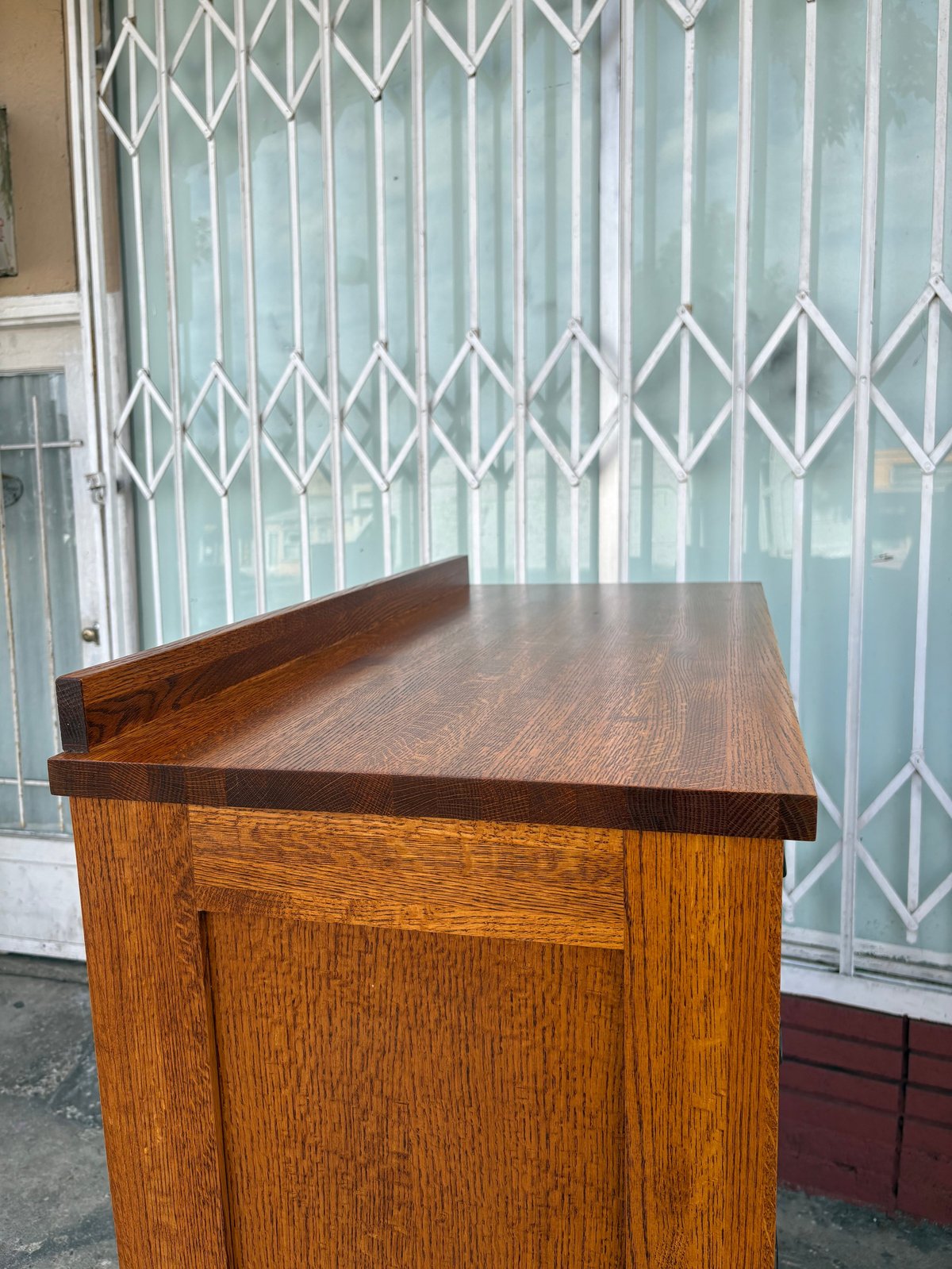 Wooden cabinet with dark countertop in front of light blue accordion security gate