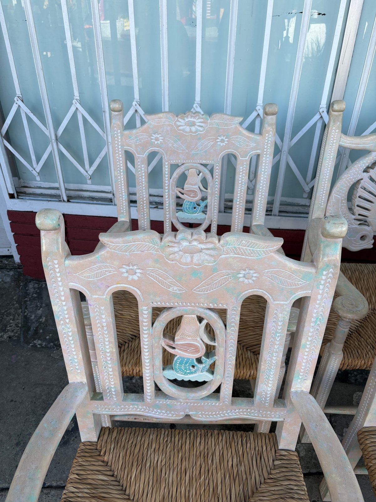 Ornate white woven chair with geometric patterns and turquoise accents, displayed indoors