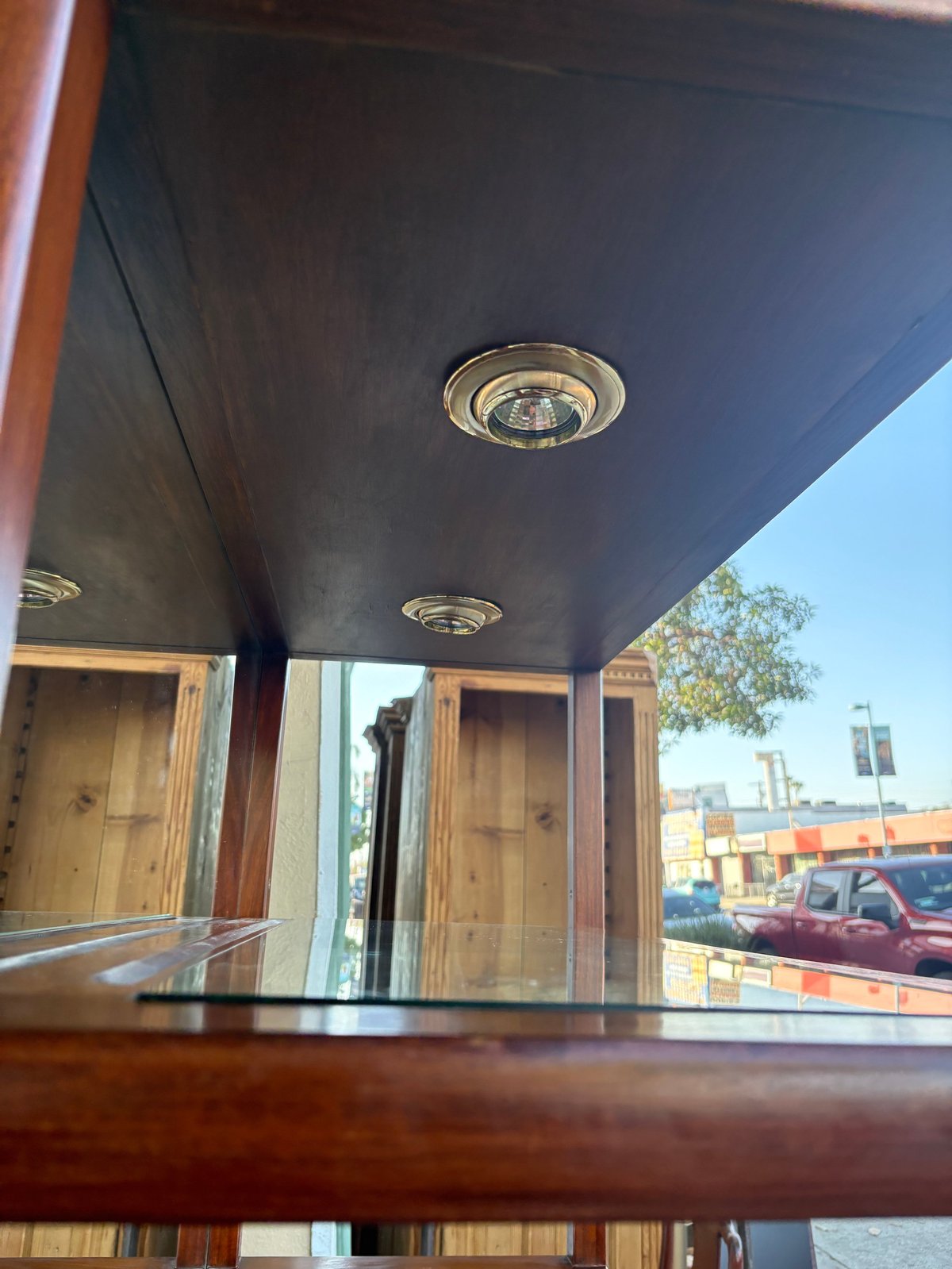 Interior view of a wooden structure with recessed ceiling lights, windows, and a view of a shipping port with stacked cargo containers outside